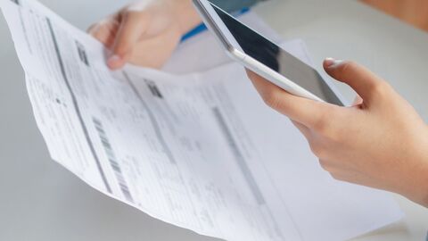 Eine Person fotografiert mit dem Smartphone ein Formular