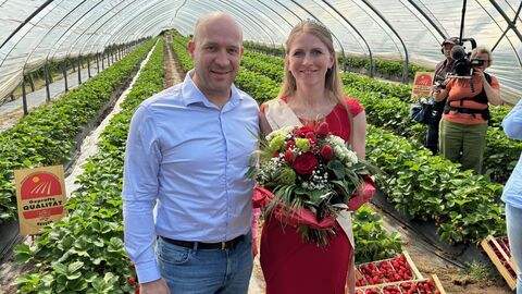 Landwirtschaftsminister Ingmar Jung und die neue Erdbeerkönigin Wiebke I. (Wiebke Jung) stehen in einem Gewächshaus vor Erdbeerfeldern.