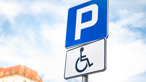 Ein blaues Schild mit einem weißen P darauf. Darunter ist ein weißes Schild mit einer schwarzen Zeichnung eines Rollstuhlfahrers.