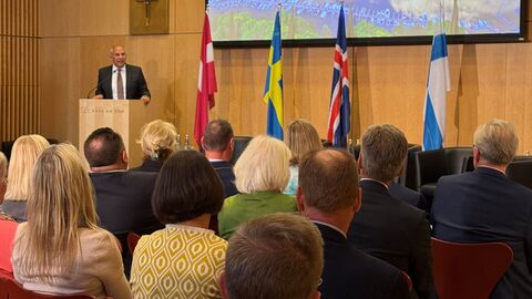 Person hält Rede an Rednerpult vor Publikum